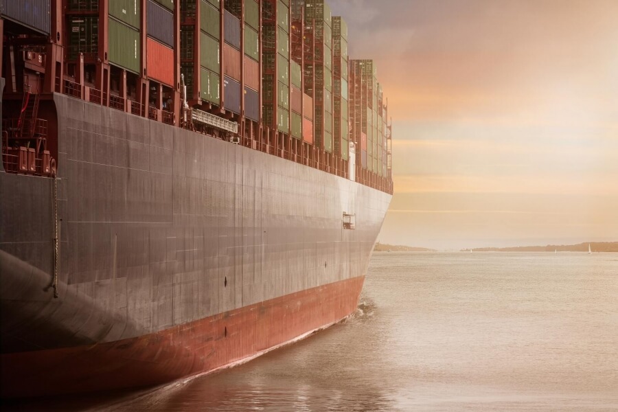Ein Containerschiff fährt Richtung Sonnenaufgang