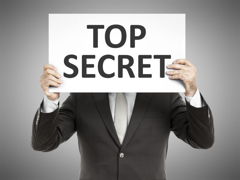 Mann im Anzug hält Plakat mit der Aufschrift "Top Secret"