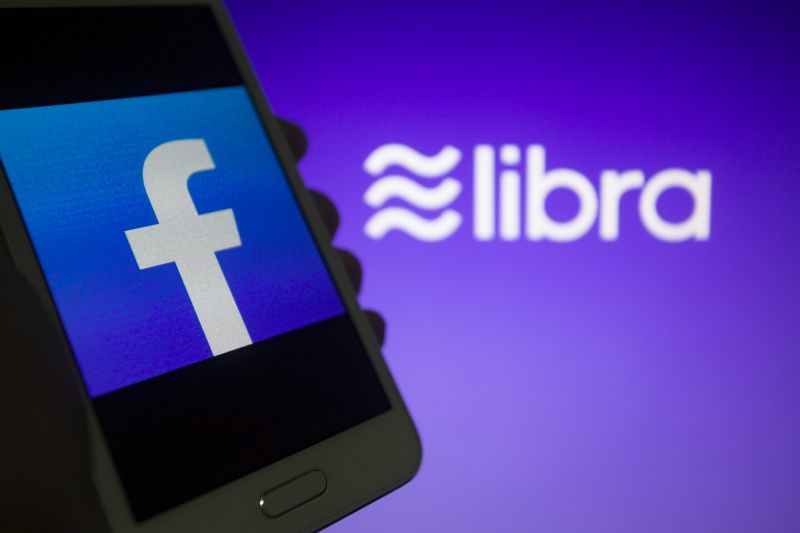 Facebook Logo auf Handy und Libra Logo im Hintergrund