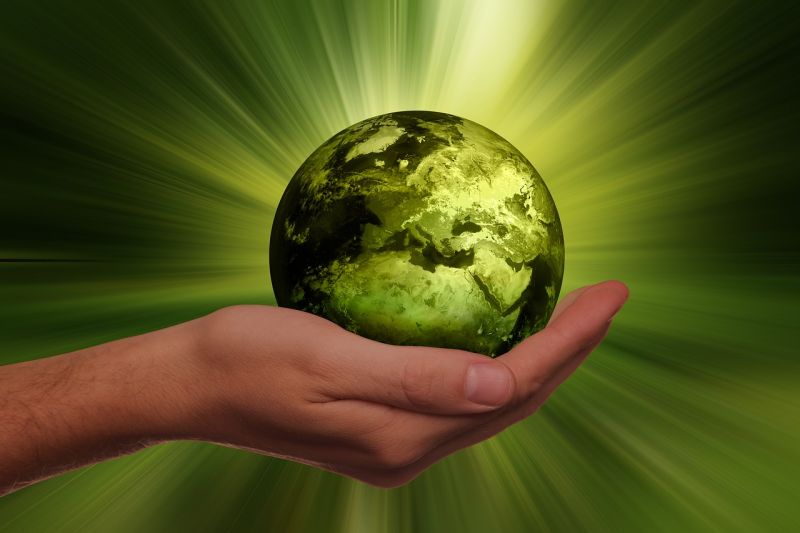 Eine Hand hält eine grüne, strahlende Erde.