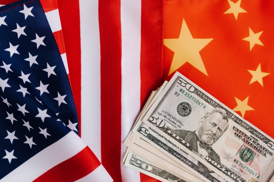 Flaggen der USA und China, außerdem ein Bündel Dollarscheine