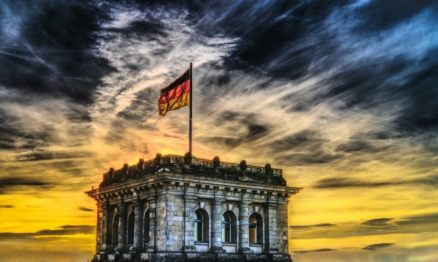 Ein Turm des Bundestages mit wehender Deutschlandfahne im Sonnenuntergang