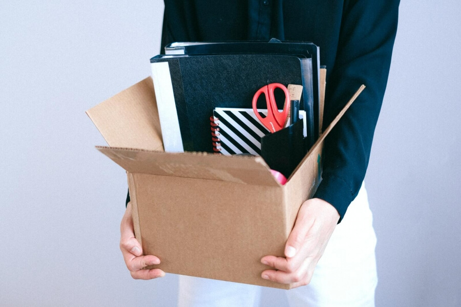 Eine Frau trägt Büro-Materialien in einer Kiste