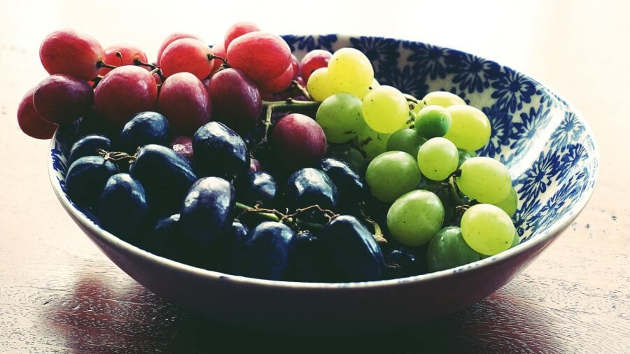 Eine Schale mit Weintrauben in den Farben Grün, Schwarz und Rot