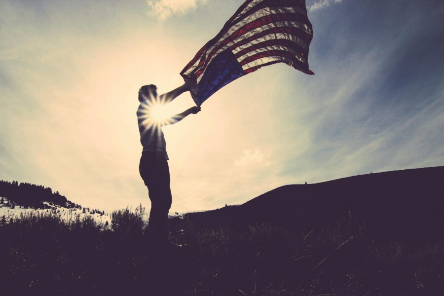 Ein Mensch schwenkt eine US-Flagge im Sonnenuntergang