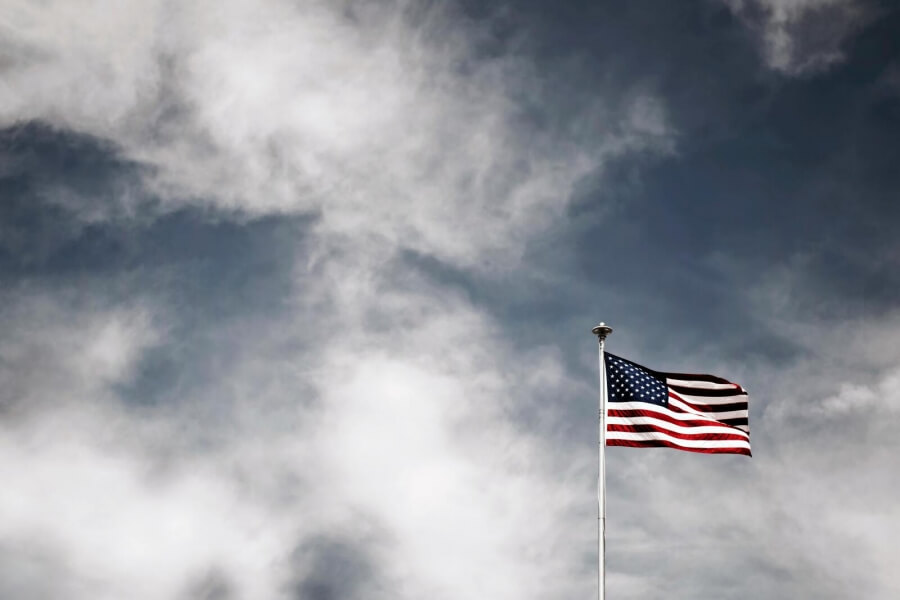 Eine US-Flagge vor einem bewölkten, dunklen Himmel
