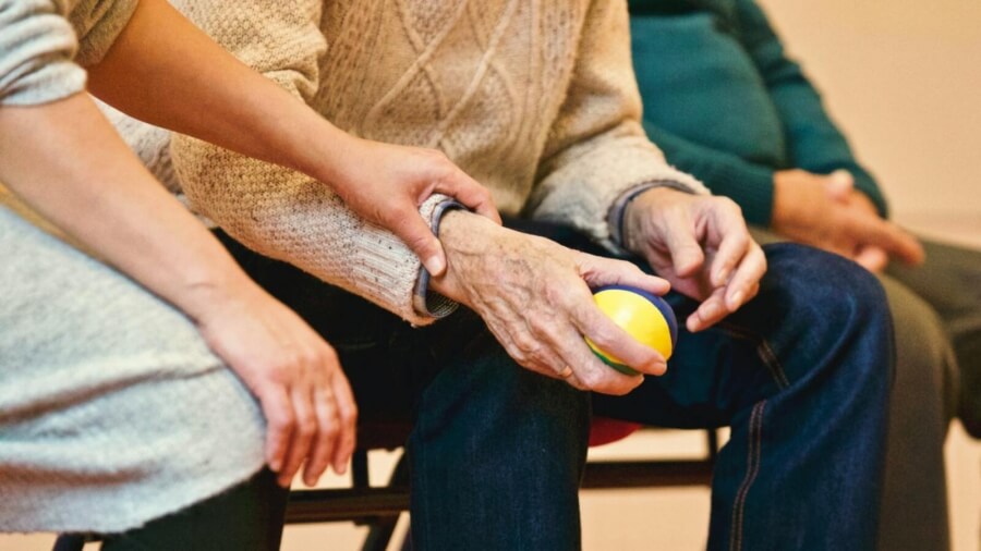 Alte Hände halten einen Ball in einer Senioren-Sportgruppe