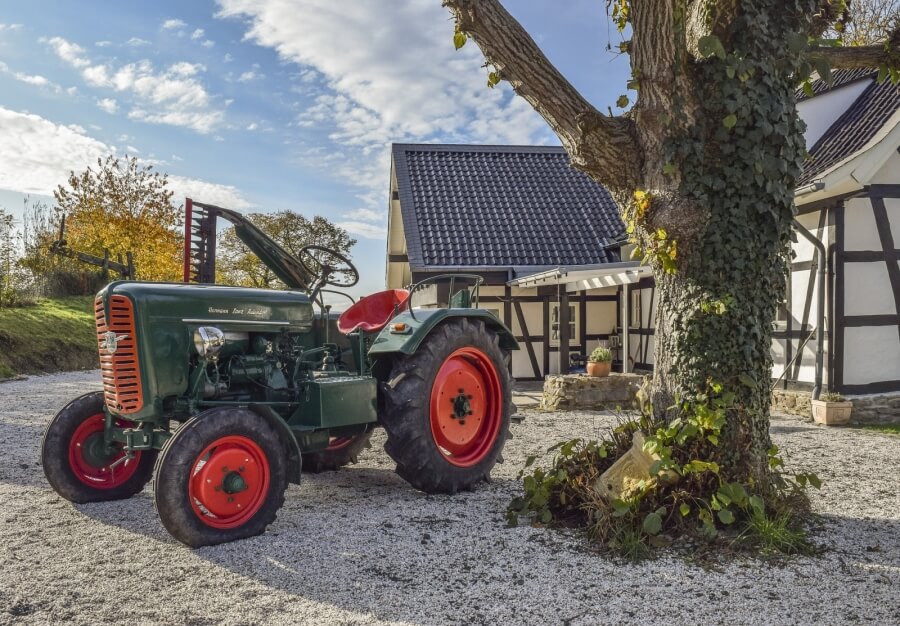 Ein Oldtimer-Traktor steht vor einem Haus