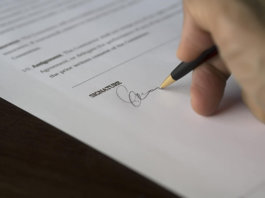 Eine Hand unterschreibt mit einem Kugelschreiber ein Dokument