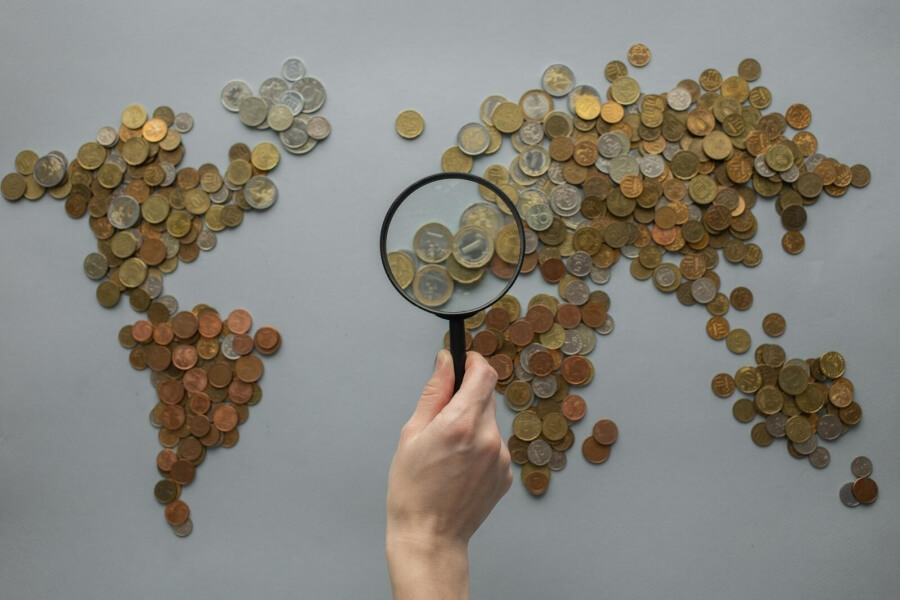Eine Lupe untersucht eine Karte, gelegt aus Euro-Münzen