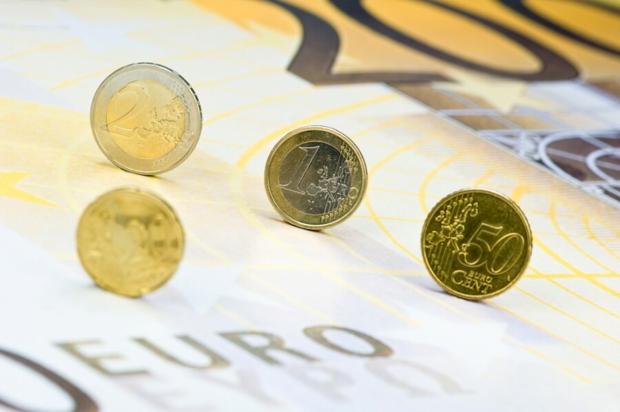 Euromünzen rollen über einen überdimensionalen 200-Euro-Geldschein