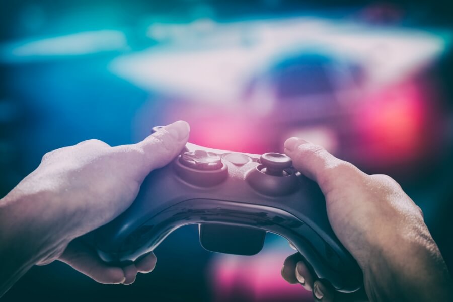 Eine Person hält einen Controller in der Hand und spielt ein Video-Spiel