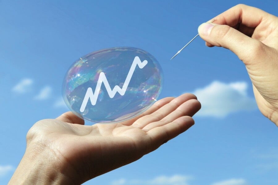 Eine Person lässt mit einer Nadel eine Blase platzen, in der ein Chart abgebildet ist als Symbol für Wirtschaft und Wachstum