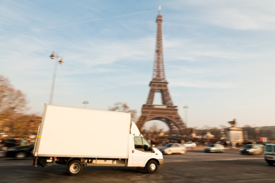 Straßenszene in Paris, ein Transporter fährt auf der Straße, im Hintergrund der Eiffelturm