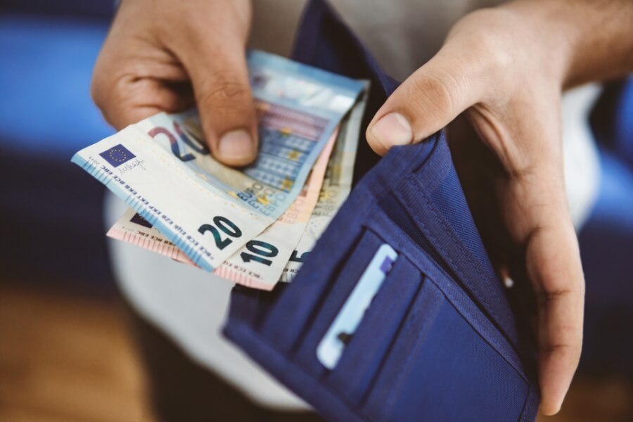 Eine Person entnimmt Geld aus ihrem Portemonnaie
