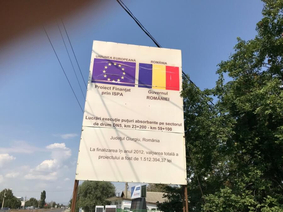 Schild in Rumänien mit Flaggen der EU und Rumäniens, Verweis auf EU-gefördertes Infrastrukturprojekt