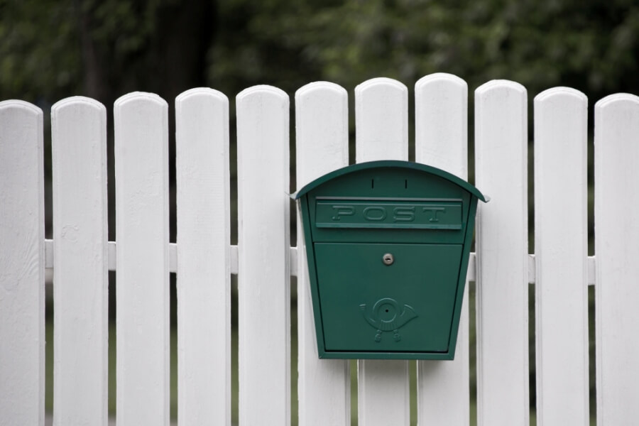 Weißer Zaun mit grünem Briefkasten