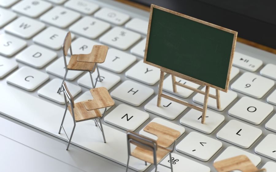 Miniatur-Stühle und eine Miniatur-Tafel stehen auf einer Tastatur