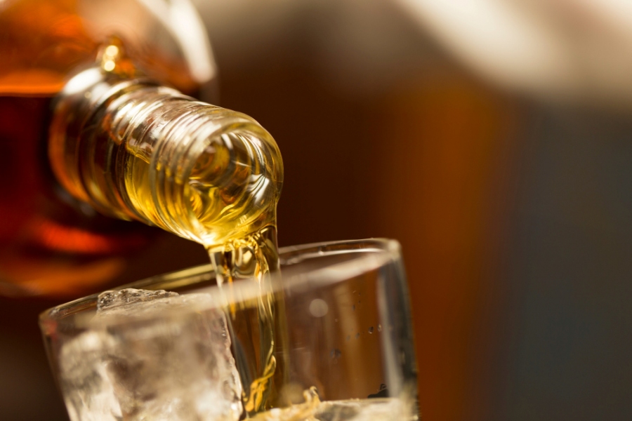 Whisky wird in ein Glas mit Eiswürfeln gefüllt
