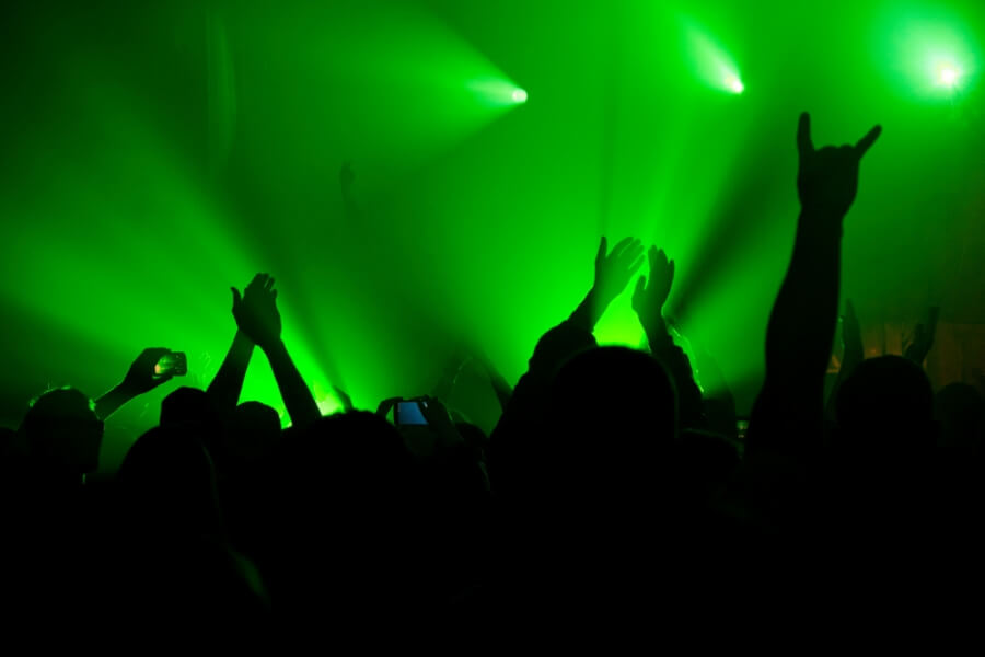Besucher eines Konzerts werden von grünem Licht beschienen