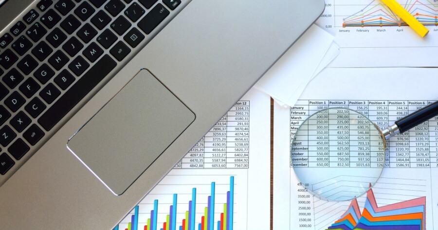 Laptop und Unterlagen mit Finanzdaten auf einem Tisch