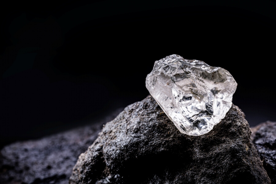 Ungeschliffener Rohdiamant liegt auf einem schwarzen Stein