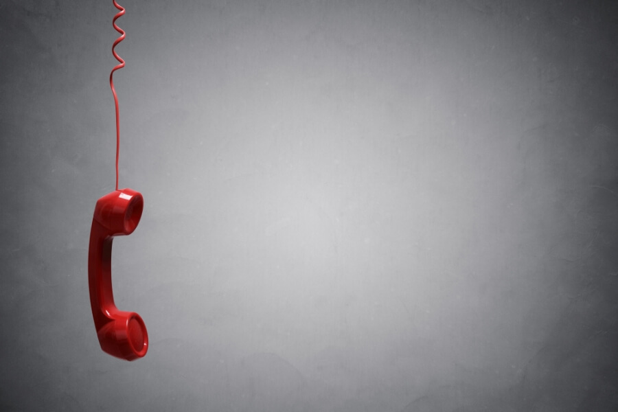 Rotes Telefon hängt herab und baumelt an einer roten Schnur