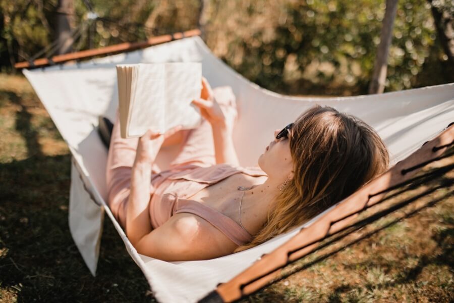 Frau liegt in einer Hängematte und liest ein Buch