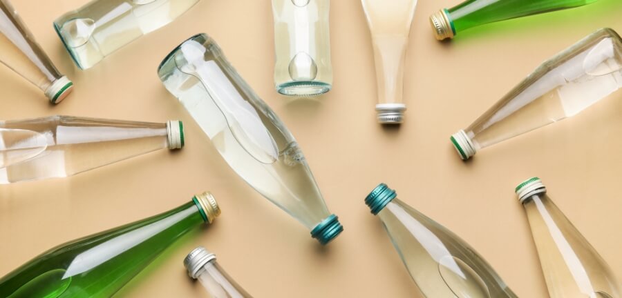 Verschiedene Glasflaschen, gefüllt mit Wasser, liegen auf einer hellen Oberfläche