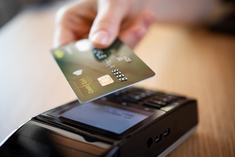 Person zahlt mit Kreditkarte an einem Kartenterminal