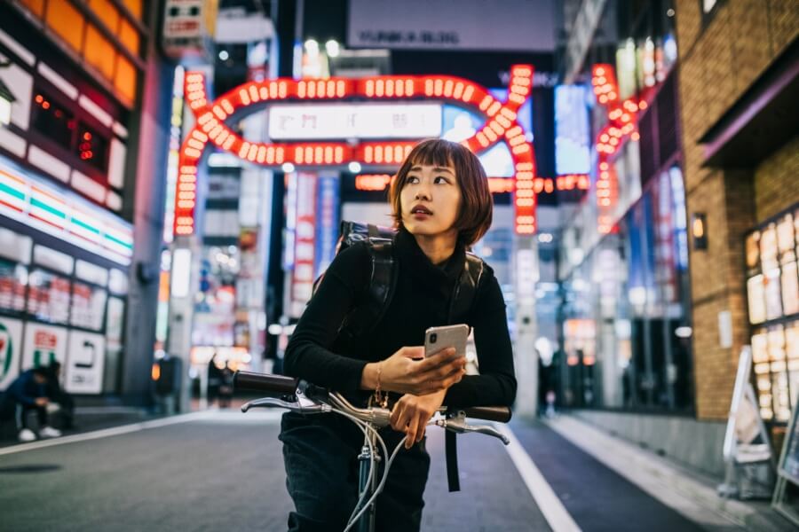 Junge asiatische Frau mit Smartphone in einer Stadt