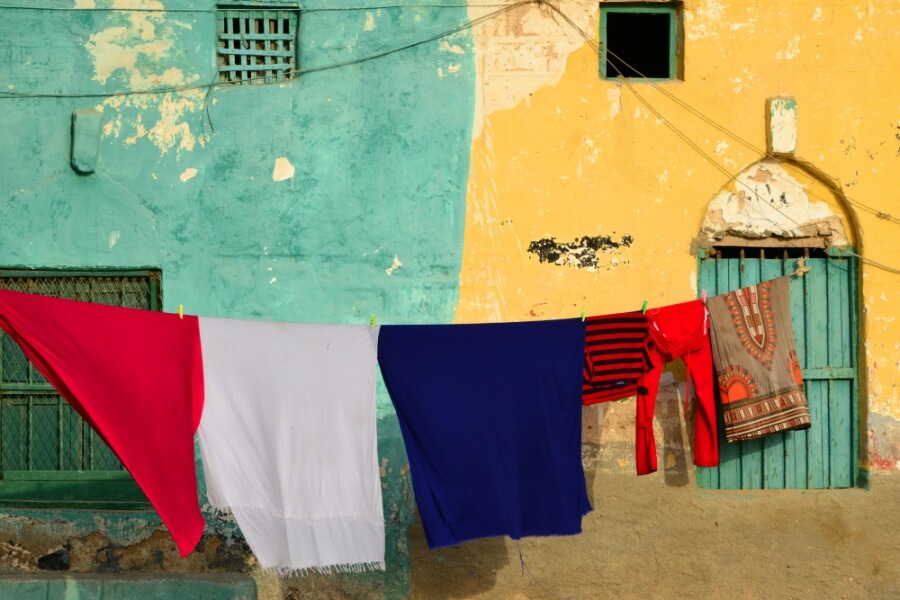 Auf einer Wäscheleine hängen ein rotes, ein weißes und ein blaues Laken.