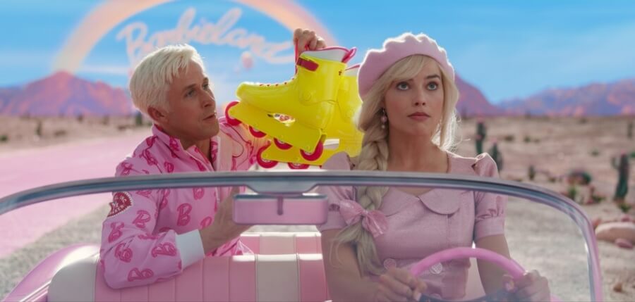 Szene aus dem Kinofilm "Barbie": Barbie (Margot Robbie) und Ken (Ryan Gosling) sitzen in einem rosa Auto