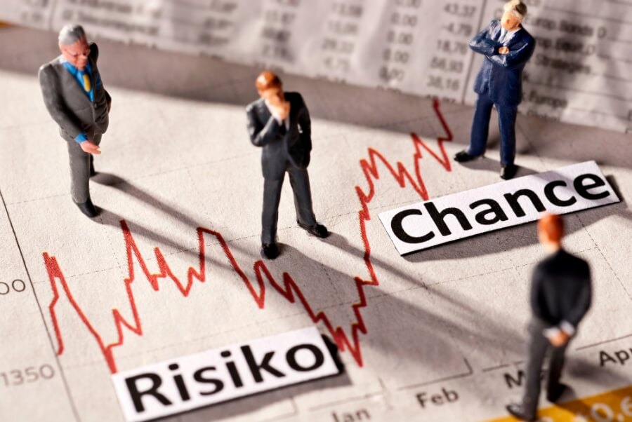 Miniaturfiguren stehen auf einer Zeitungsseite. Auf der Seite befindet sich ein Börsenchart mit der Aufschrift "Risiko" und Chance. Symbolbild Geldanlage.